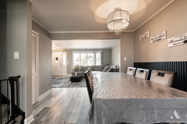 a dining room with wooden floor a chandelier a wooden table and chairs