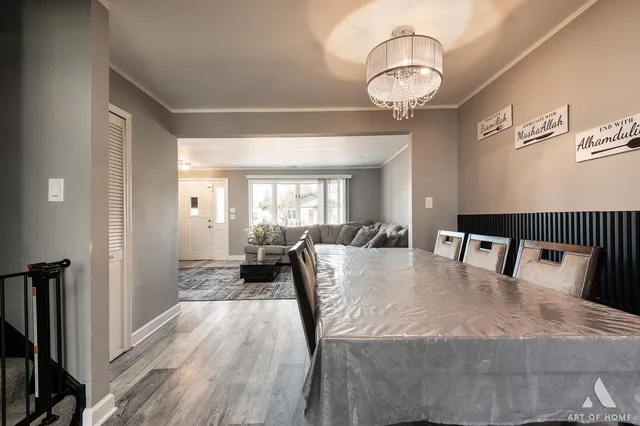 a dining room with wooden floor a chandelier a wooden table and chairs