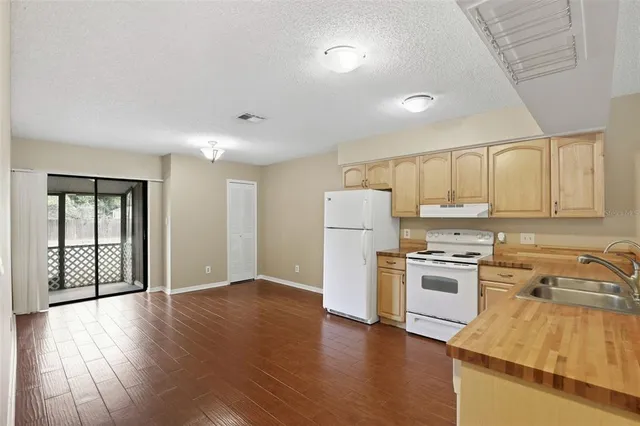 a kitchen with granite countertop a refrigerator a stove top oven and sink