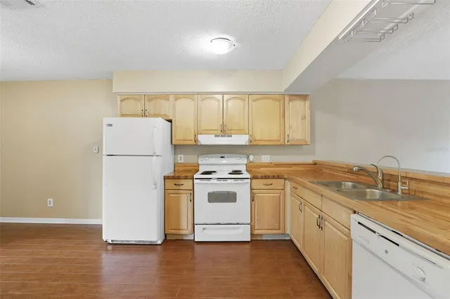 a white kitchen with wooden floor and white stainless steel appliances