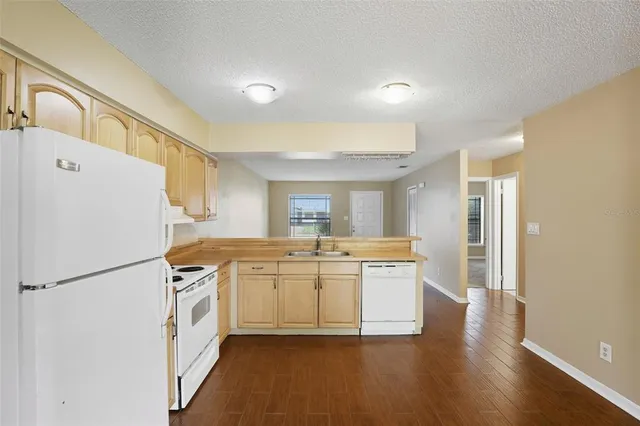 a kitchen with stainless steel appliances a refrigerator a stove a sink and white cabinets with wooden floor