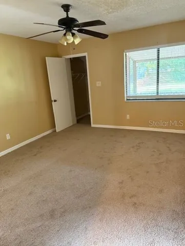 an empty room with windows and fan