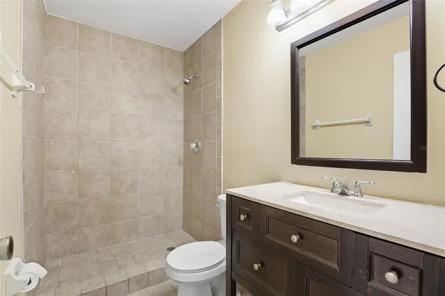 a bathroom with a granite countertop sink toilet a mirror a vanity and shower