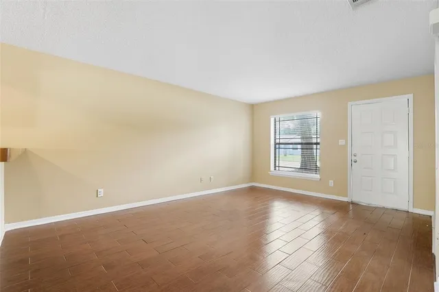 a view of an empty room with wooden floor and a window