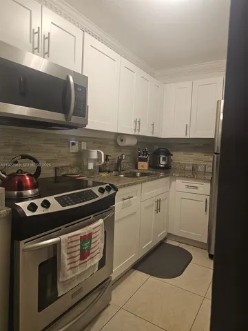 a kitchen with a stove and white cabinets