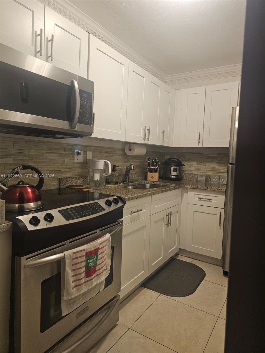 8411 Northwest 8th Street, Unit 111 Miami, FL 33126 - Photo 12 of 27 a kitchen with a stove and white cabinets