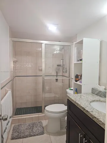 a bathroom with a granite countertop sink a toilet and shower