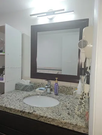 a bathroom with a granite countertop sink and a mirror