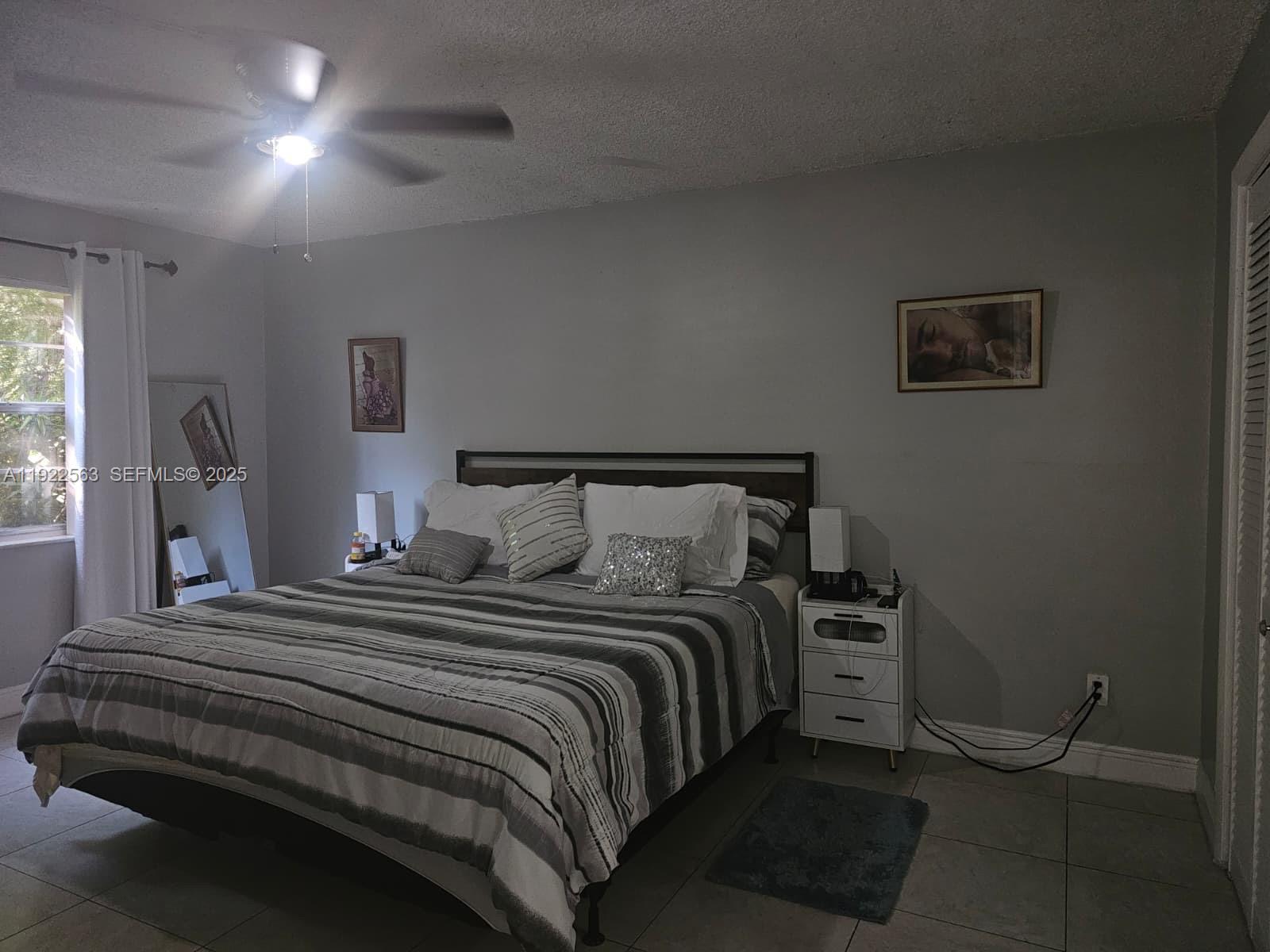8411 Northwest 8th Street, Unit 111 Miami, FL 33126 - Photo 19 of 27 a bedroom with a bed and a lamp with window