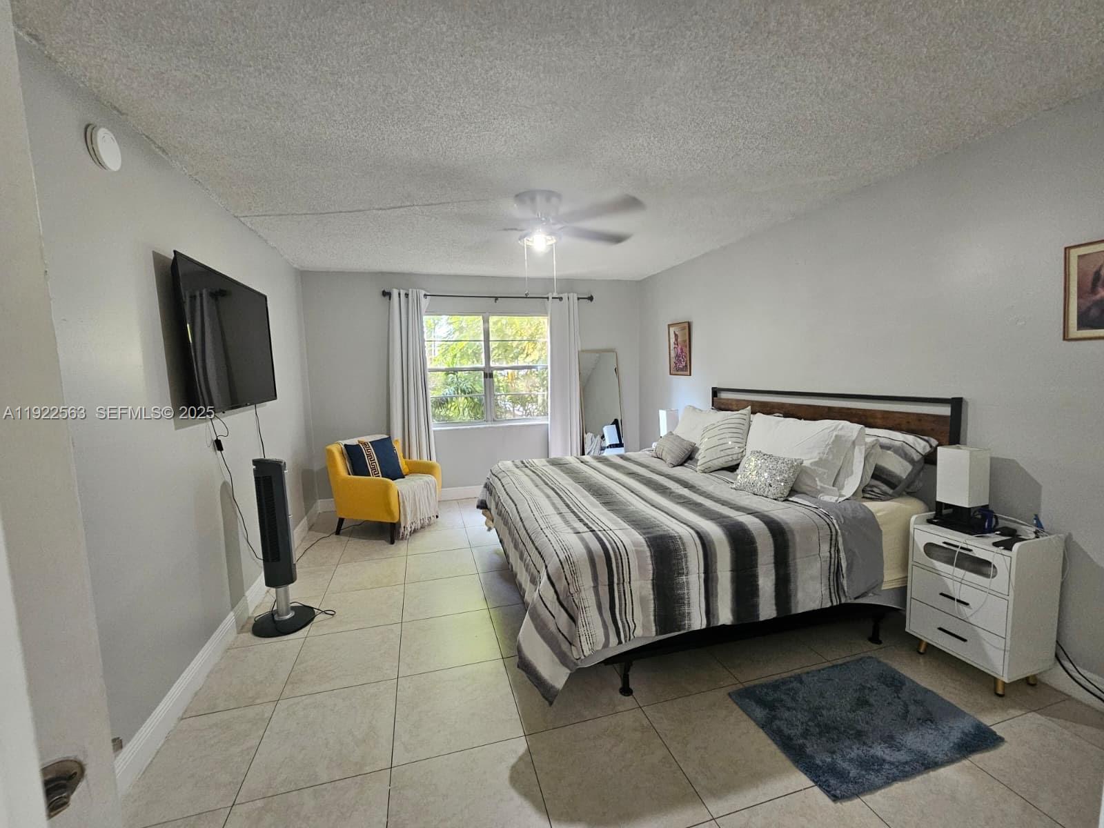 8411 Northwest 8th Street, Unit 111 Miami, FL 33126 - Photo 21 of 27 a spacious bedroom with a bed and a flat screen television