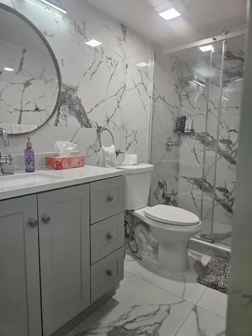 a bathroom with a toilet sink vanity granite and mirror