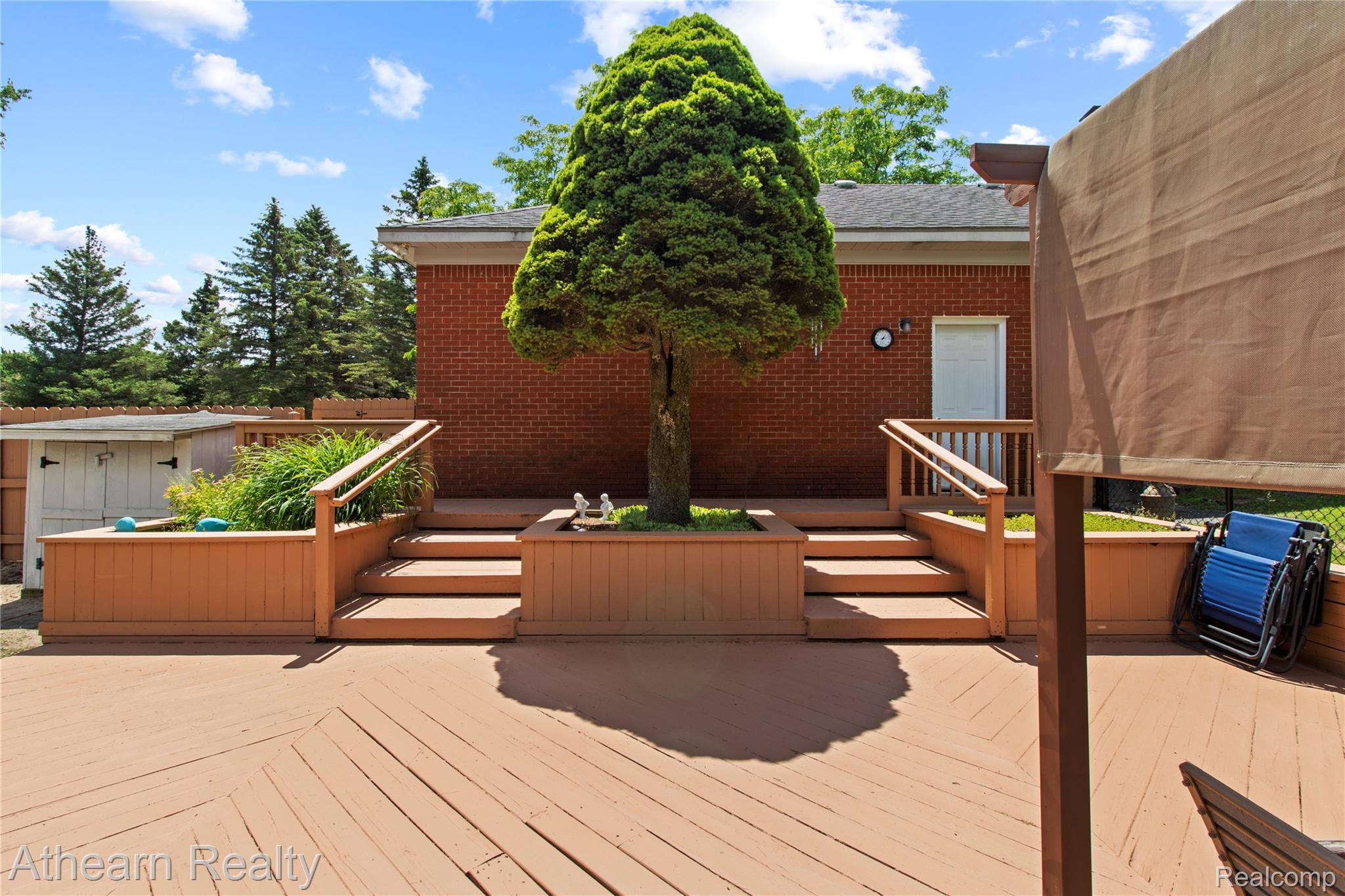 12427 Foley Road Fenton, MI 48430 - Photo 12 of 47 Expansive multi-level wood-finish deck with built-in planters and steps leading to a red brick exterior