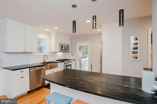 a kitchen with stainless steel appliances granite countertop a sink dishwasher stove and white countertops with wooden floor