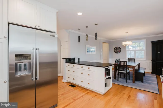 a kitchen with stainless steel appliances kitchen island granite countertop a refrigerator a stove and a dining table with wooden floor