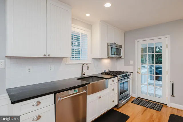 a kitchen with granite countertop a stove a sink dishwasher and white cabinets with wooden floor
