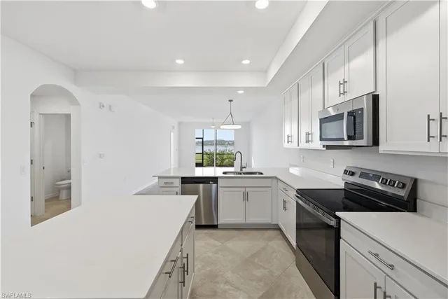 a large kitchen with a sink and dishwasher a stove with wooden floors