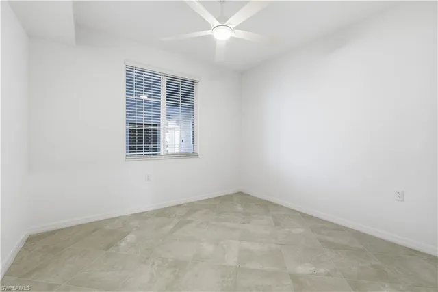 an empty room with windows and ceiling fan