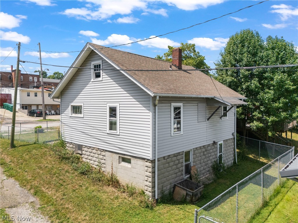 16 South State Street Rittman, OH 44270 - Photo 3 of 27 View of home's exterior featuring a chimney, roof with shingles, and a fenced backyard