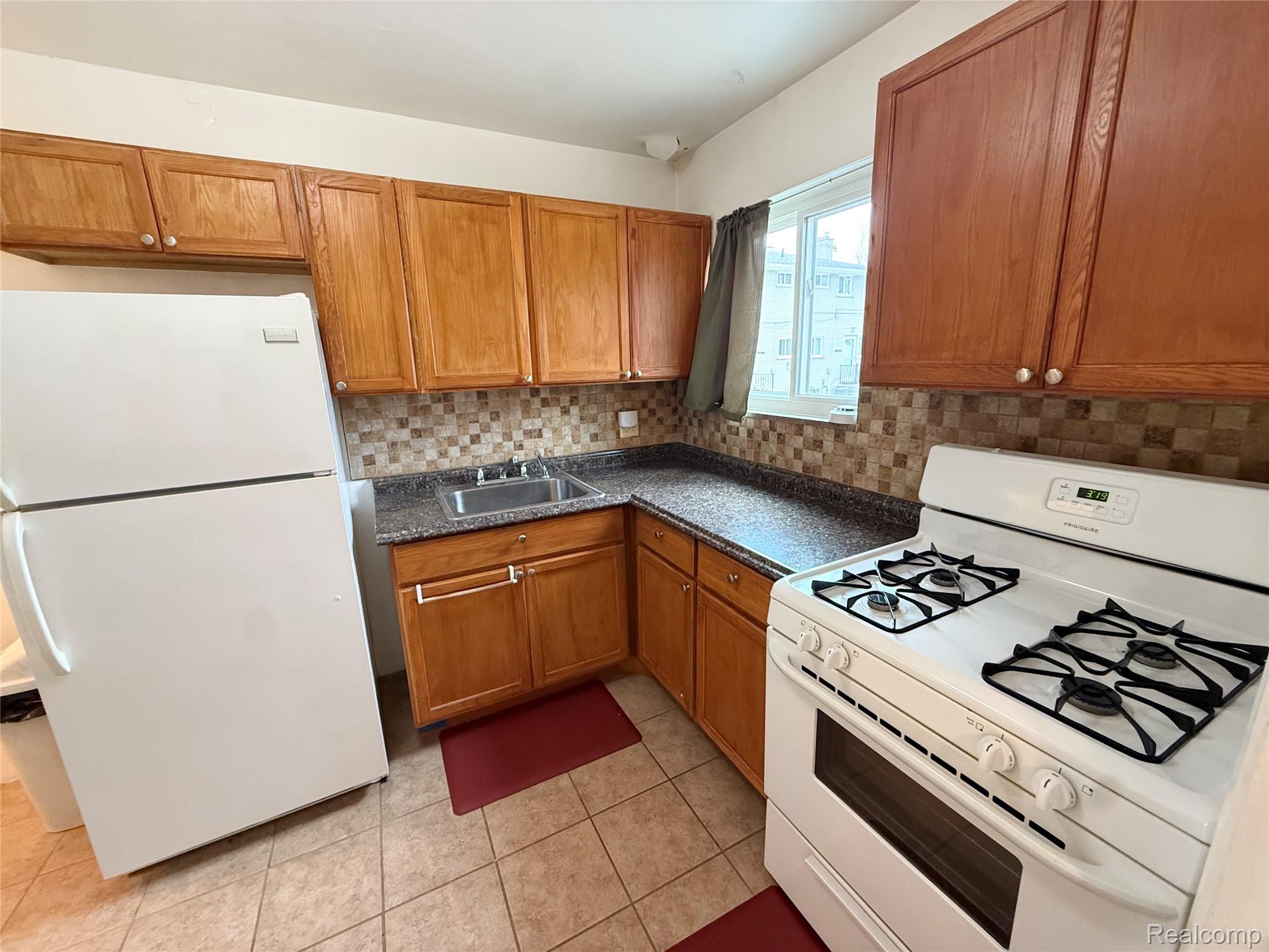 11012 Middlebelt Road Livonia, MI 48150 - Photo 5 of 14 Kitchen featuring wood-finish cabinetry, patterned tile backsplash, granite-look countertops, and tile flooring