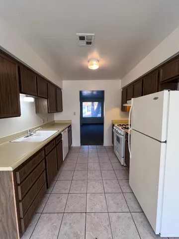 a kitchen with a refrigerator a stove top oven and cabinets