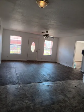 a view of an empty room with window and chandelier fan