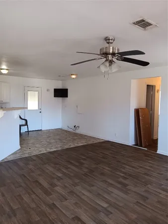 a view of empty room with wooden floor and fan