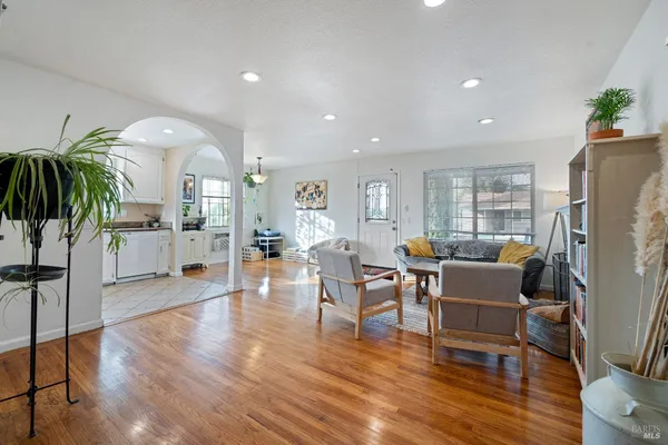 a living room with furniture a wooden floor and a dining table
