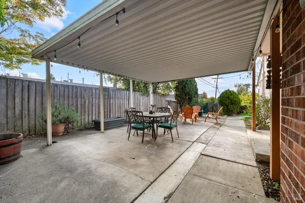 a view of a patio with a table and chairs and a barbeque