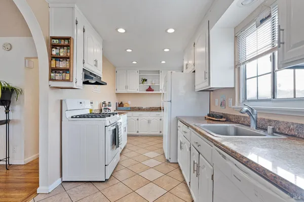a kitchen with granite countertop white cabinets and white appliances