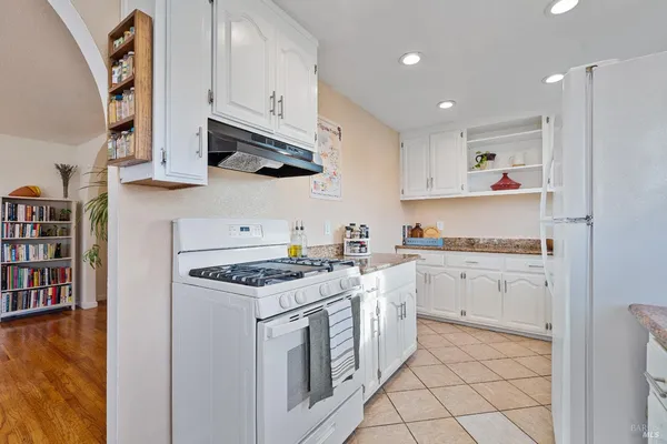 a kitchen with granite countertop white cabinets and white appliances