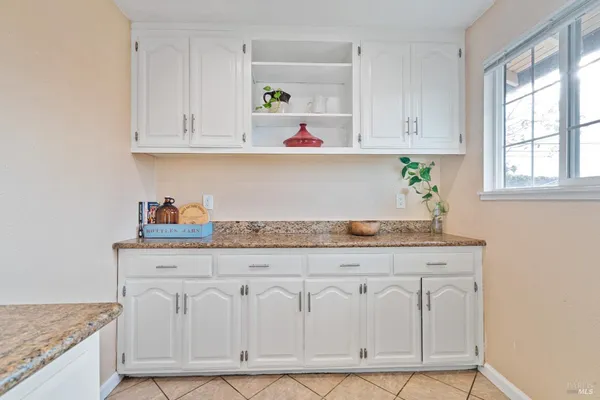 a kitchen with white cabinets and window