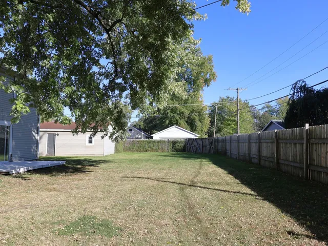 a backyard of a house with table and chairs under an umbrella