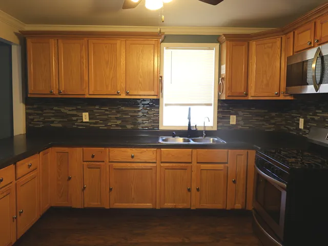 a kitchen with stainless steel appliances granite countertop a sink a stove and a microwave