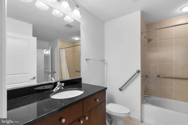 a bathroom with a granite countertop sink toilet a mirror and shower