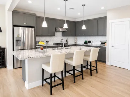 a kitchen with stainless steel appliances a dining table chairs sink and cabinets