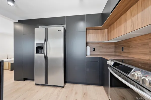 a kitchen with metallic refrigerator and wooden floor