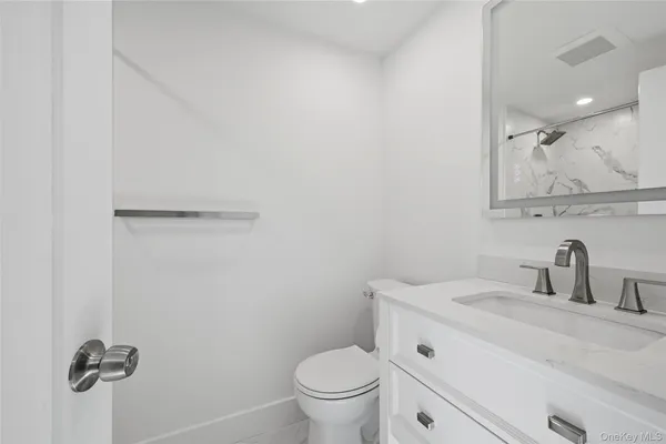a bathroom with a toilet sink vanity and mirror