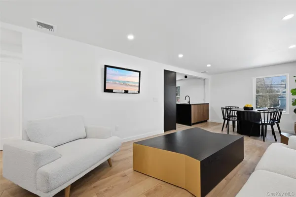 a living room with furniture wooden floor and a kitchen view