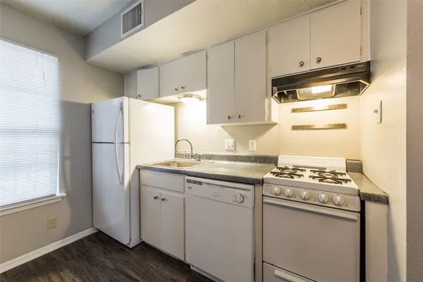 a kitchen with stainless steel appliances a refrigerator a sink and white cabinets