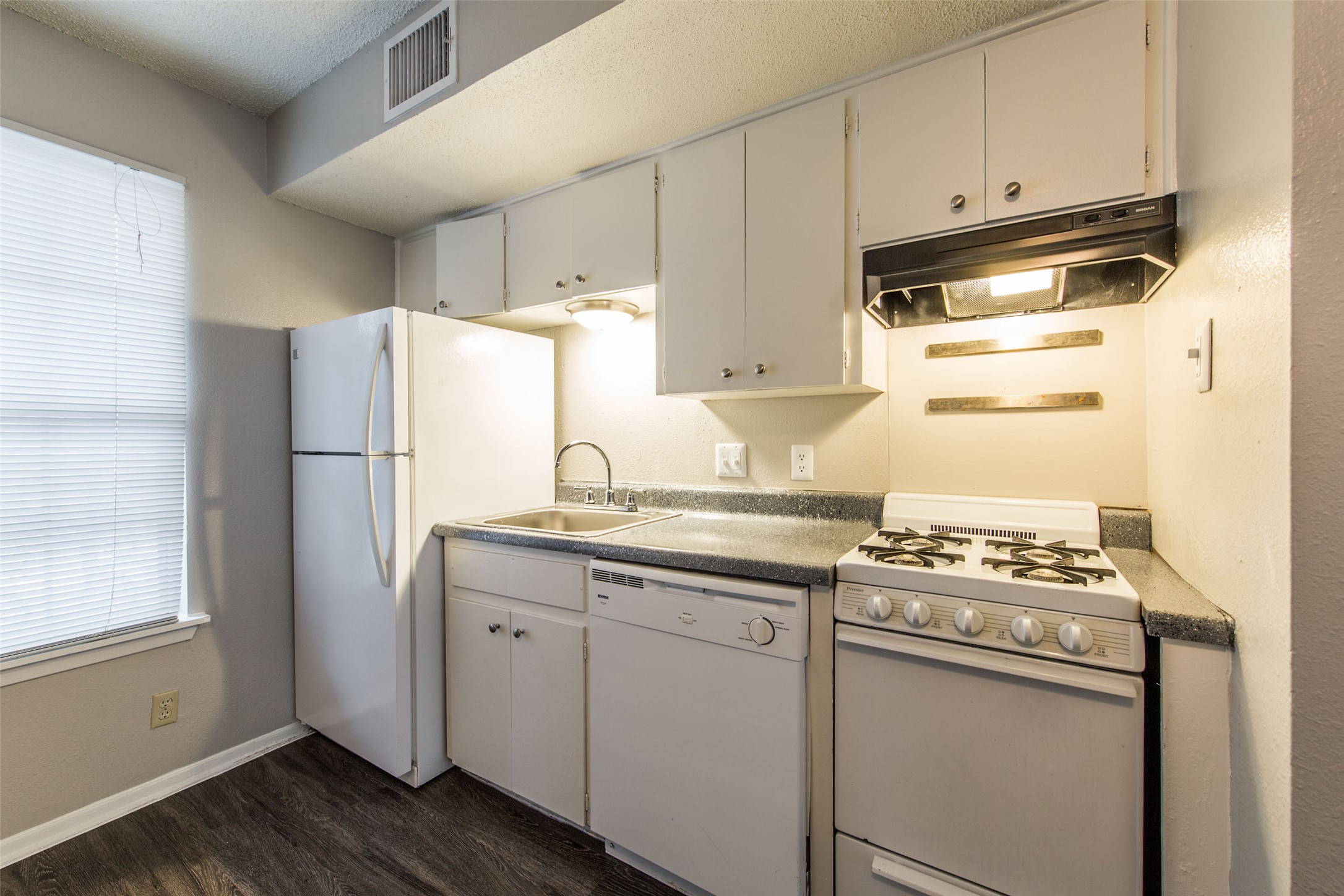 a kitchen with stainless steel appliances a refrigerator a sink and white cabinets