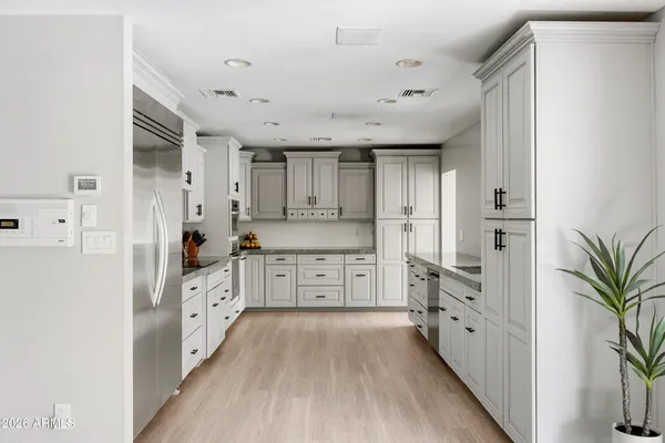 a large kitchen with cabinets a sink a window and stainless steel appliances