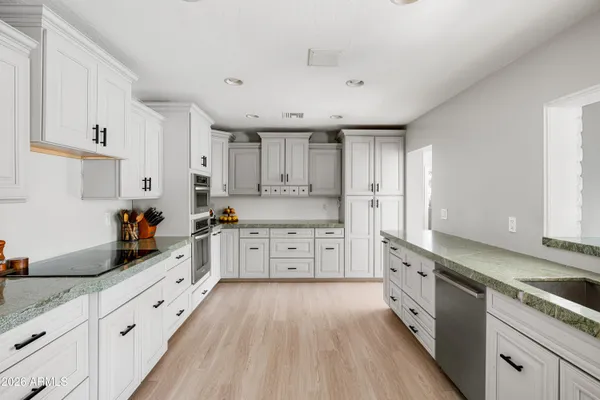 a large kitchen with stainless steel appliances granite countertop a lot of counter space and wooden floors