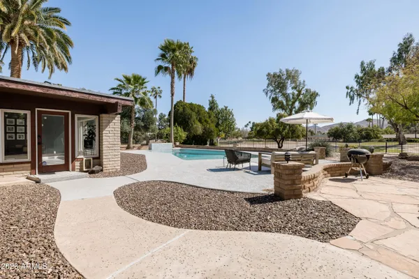a view of a swimming pool with a yard and palm trees
