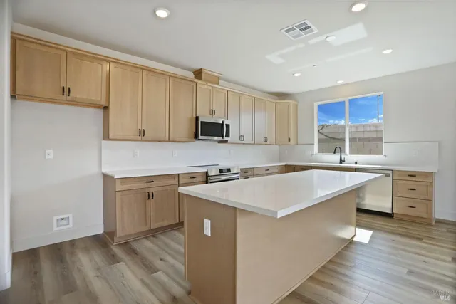 a kitchen with stainless steel appliances granite countertop a sink dishwasher stove and white cabinets with wooden floor