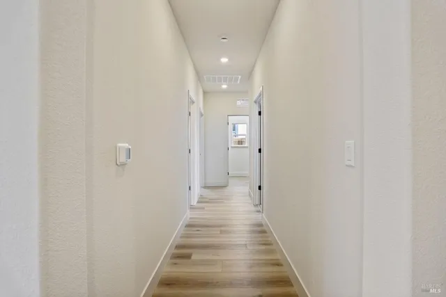 a view of a hallway with wooden floor and a bathroom