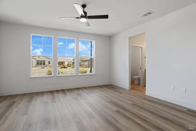 a view of an empty room with a window and wooden floor