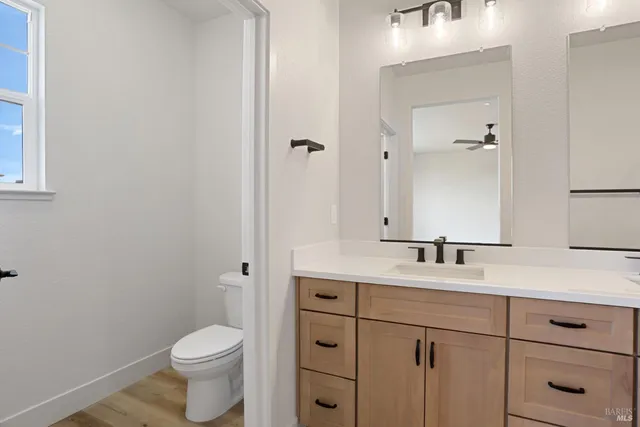 a bathroom with a toilet a sink a vanity and mirror