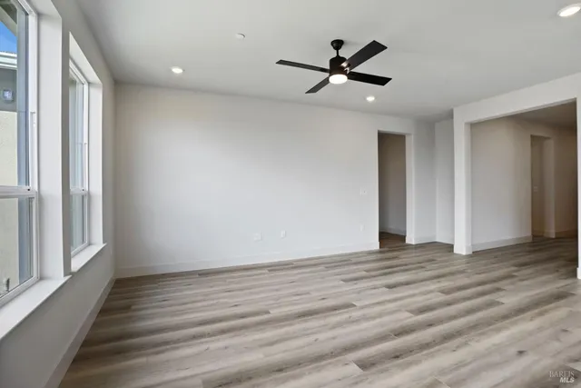 a view of empty room with wooden floor and fan