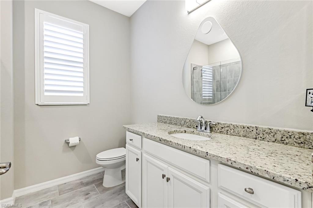 1603 Santiago Circle Naples, FL 34113 - Photo 12 of 46 a bathroom with a granite countertop toilet sink and mirror