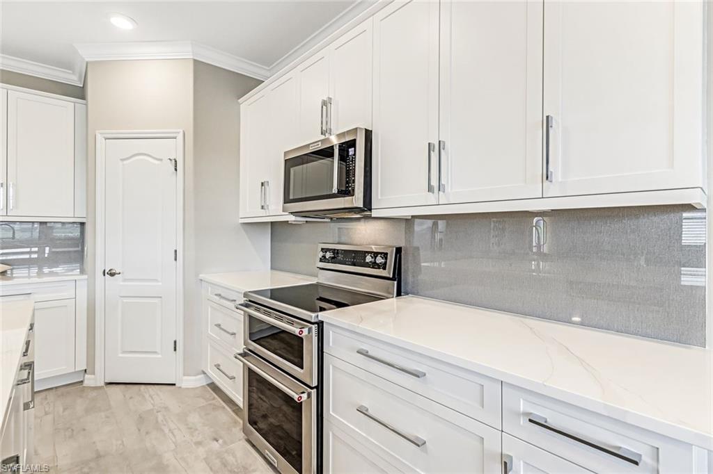 1603 Santiago Circle Naples, FL 34113 - Photo 20 of 46 a kitchen with white cabinets and stainless steel appliances